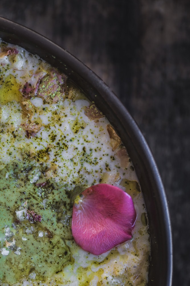 Cardamom rose porridge with matcha dust, sprouted pumpkin seed butter, and rose petal
