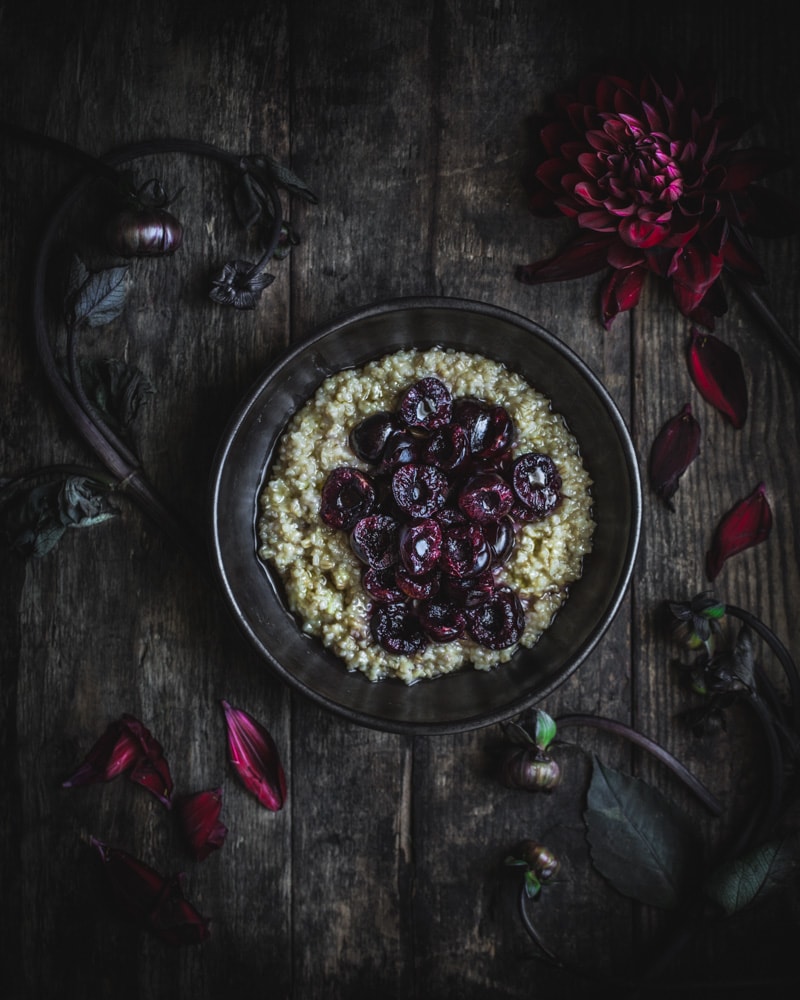 Bowl of steel cut oats topped with fresh cherries and ginger