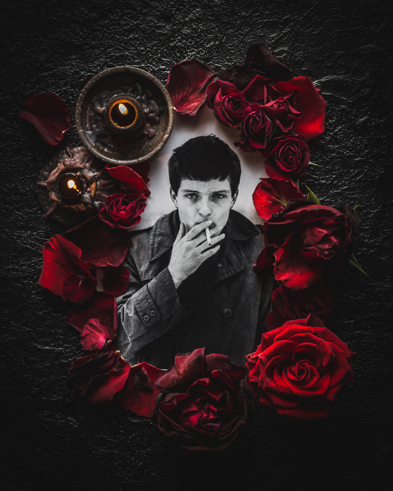 Ian Curtis smoking grave memorial surrounded by red roses and candles