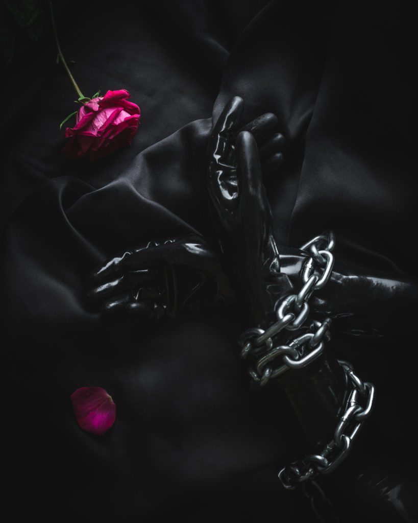 BDSM fetish vinyl gloves wrapped in chains on black silk